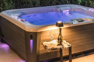 a hot tub with a bottle of wine and two glasses at Amie Chalet in Santa Cristina in Val Gardena