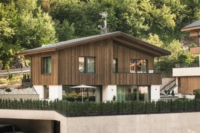 a house with a wooden facade with trees at Amie Chalet in Santa Cristina in Val Gardena