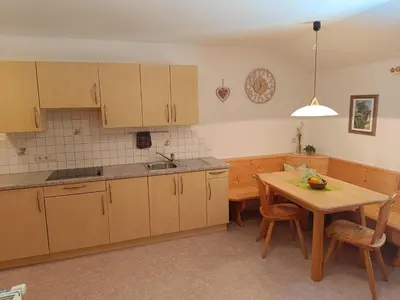 a kitchen with wooden cabinets and a table with chairs at Oberschlichterhof in Longomoso