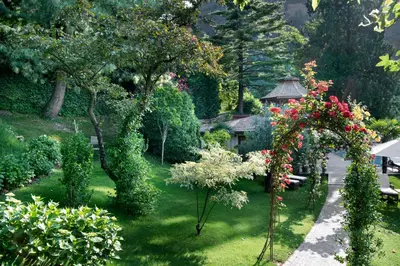 a garden with flowers and a gazebo in the background at Relais & Chateaux Hotel Castel Fragsburg in Merano