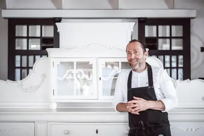 a man wearing an apron standing in front of a cabinet at Relais & Chateaux Hotel Castel Fragsburg in Merano