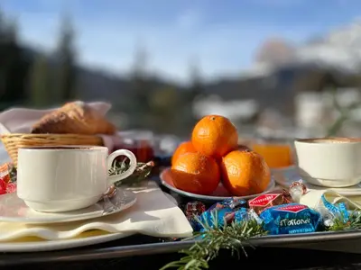 a table with a cup of coffee and oranges at Hotel Mirage in Cortina dʼAmpezzo