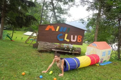a young boy laying on the grass in front of a playground at Hotel Mirage in Cortina dʼAmpezzo