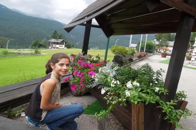 a young woman sitting on a balcony with flowers at Hotel Mirage in Cortina dʼAmpezzo