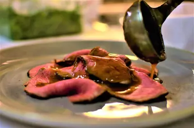a plate with a piece of meat with a spoon at Hotel Mirage in Cortina dʼAmpezzo