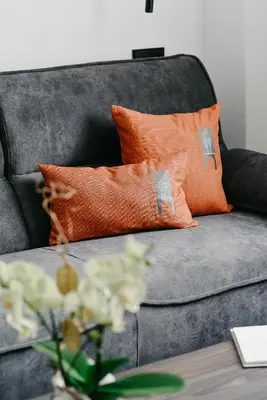 a gray couch with orange pillows and a table at Nepomuk rooms in Vipiteno