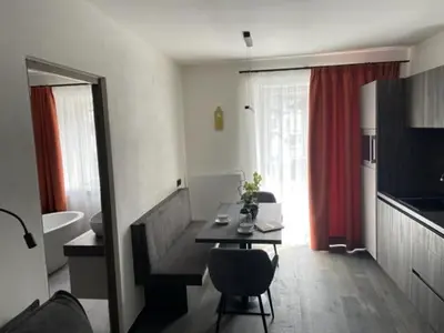 a living room with a table and a bathroom at Nepomuk rooms in Vipiteno