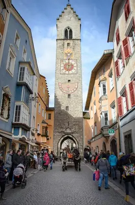 a clock tower in a street with a crowd of people at Nepomuk rooms in Vipiteno