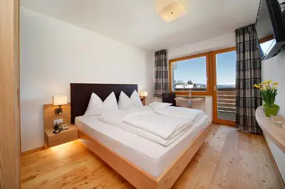 a bedroom with a large white bed with a large window at Gasthof Weber in Petersberg