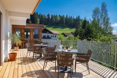 a patio with tables and chairs on a wooden deck at Gasthof Weber in Petersberg