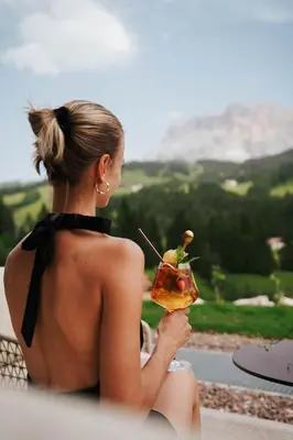a woman sitting on a ledge holding a drink at Badia Hill in Badia