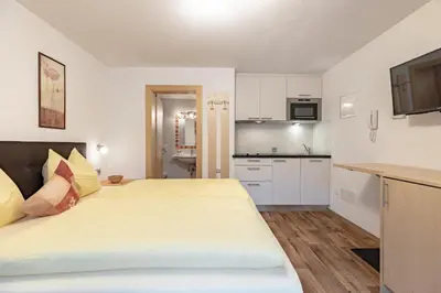 a bedroom with a large bed and a kitchen at Apartments Soval in Santa Cristina in Val Gardena