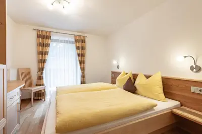 a bedroom with a bed with yellow sheets and a window at Apartments Soval in Santa Cristina in Val Gardena