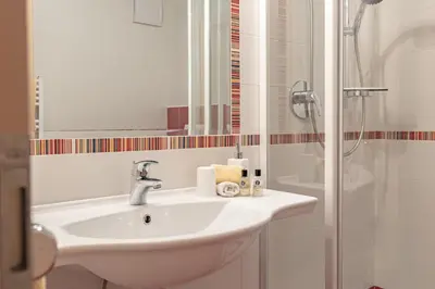 a white bathroom with a sink and a shower at Apartments Soval in Santa Cristina in Val Gardena