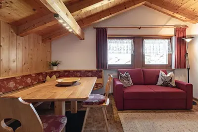 a living room with a red couch and a wooden table at Apartment Ruiel in Santa Cristina in Val Gardena