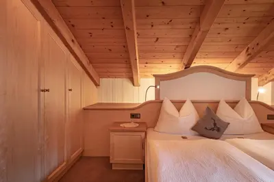 a bedroom with a large white bed with a wooden ceiling at Apartment Ruiel in Santa Cristina in Val Gardena