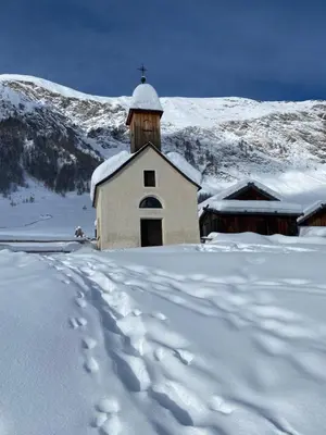 a snow covered church with a snow covered mountain at Villa Silvia in Naz-Sciaves