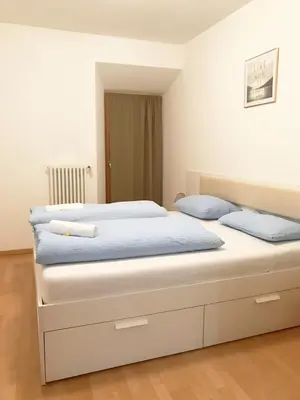 a bedroom with a large white bed with blue pillows at Argentieri Guesthouse in Bolzano