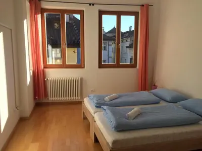 two beds in a room with two windows at Argentieri Guesthouse in Bolzano