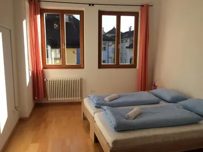 two beds in a room with two windows at Argentieri Guesthouse in Bolzano