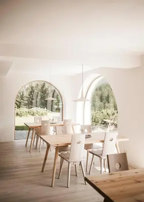 a dining room with wooden tables and white chairs at Karerhof in Nova Levante