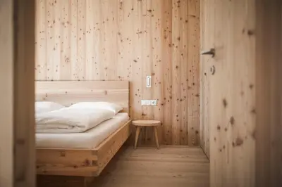 a bedroom with a bed and a wooden wall at Karerhof in Nova Levante