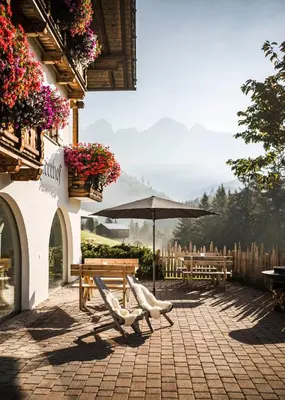 a patio with two chairs and an umbrella at Karerhof in Nova Levante