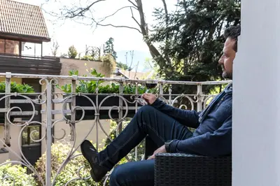 a man sitting on a fence looking at his cell phone at Villa Anita Rooms in Bolzano