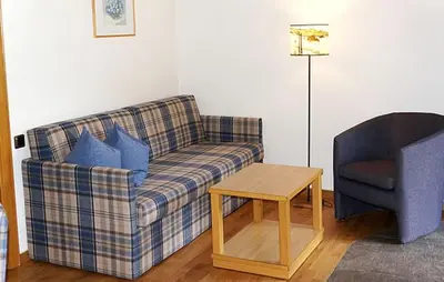 a living room with a plaid couch and a chair at Residence Cesa Callegari in Selva di Val Gardena