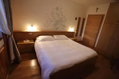 a bedroom with a large bed with two night stands at Garni Miravalle in Moena