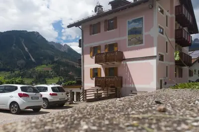 a building with two cars parked in front of it at Garni Miravalle in Moena
