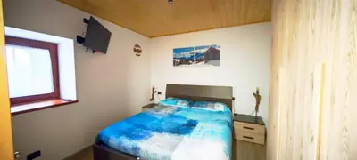 a bedroom with a bed with a blue comforter at Bilocale Nel Cuore Della Val Di Fiemme in Panchia
