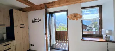 a house with a porch with a door and flowers at Bilocale Nel Cuore Della Val Di Fiemme in Panchia