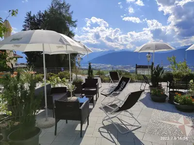 a patio with chairs and tables and umbrellas at Hotel Villa Argentina Ronzone in Ronzone