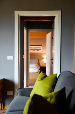 a living room with a blue couch and a bedroom at Hotel Villa Argentina Ronzone in Ronzone