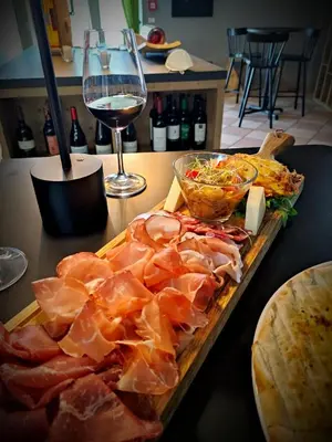 a cutting board with meat and a glass of wine at Hotel Villa Argentina Ronzone in Ronzone