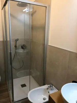a shower with a glass door next to a sink at Paradise Dolomiti flat in Falcade