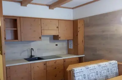 a kitchen with wooden cabinets and a sink at Paradise Dolomiti flat in Falcade