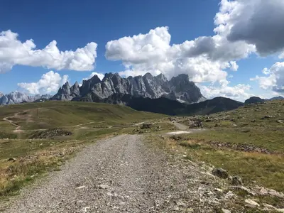 a dirt road in a field with mountains in the background at Paradise Dolomiti flat in Falcade