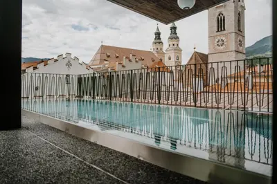 a fence around a swimming pool in front of a building at ADLER Historic Guesthouse in Bressanone