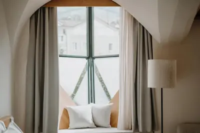 a room with a window with a couch and a lamp at ADLER Historic Guesthouse in Bressanone