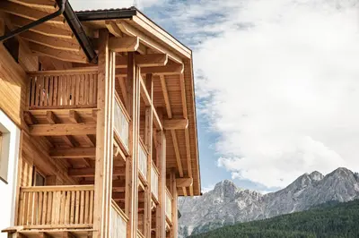a wooden building with mountains in the background at Residence Maximilian in Valdaora