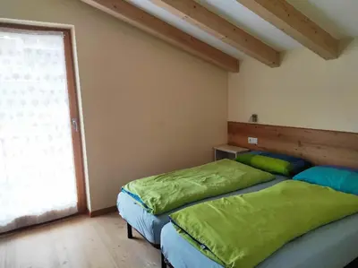 two beds in a room with a window at Appartamento Romantico a Valles in Valles