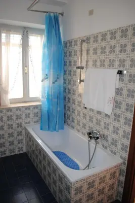 a bath tub with a blue shower curtain in a bathroom at Casa Vacanza San Martino in Fondo