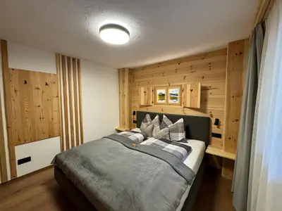 a bedroom with a large bed with wooden walls at Pliegermoar - Adults Only in Vols am Schlern