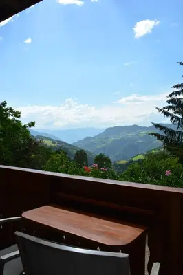 a table and chair on a balcony with a view of mountains at Pliegermoar - Adults Only in Vols am Schlern