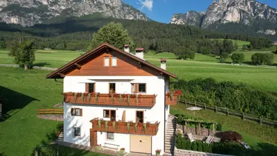 a house with a balcony and mountains in the background at Pliegermoar - Adults Only in Vols am Schlern
