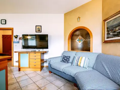 a living room with a blue couch and a flat screen tv at Apartment Ardoney-1 by Interhome in Campitello