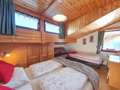 a room with two beds in a room with wooden walls at Piccola Suite sul Civetta in Colle Santa Lucia
