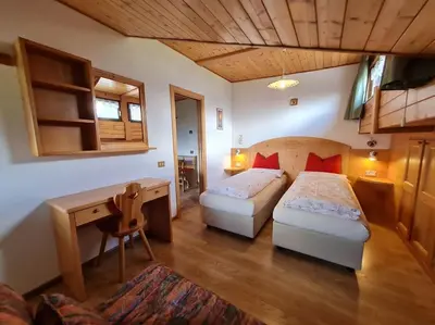 a hotel room with two beds and a desk and a desk at Piccola Suite sul Civetta in Colle Santa Lucia